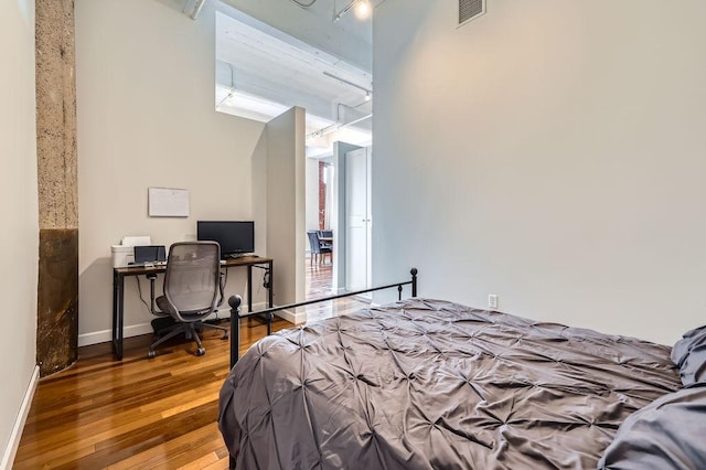 bedroom with baseboards, visible vents, and wood finished floors