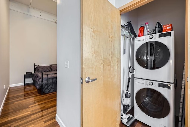 laundry room with laundry area, wood finished floors, stacked washer and clothes dryer, and baseboards