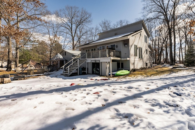 snow covered rear of property with stairs and a deck