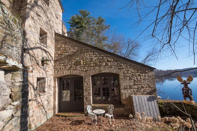 view of property exterior with stone siding and a water view