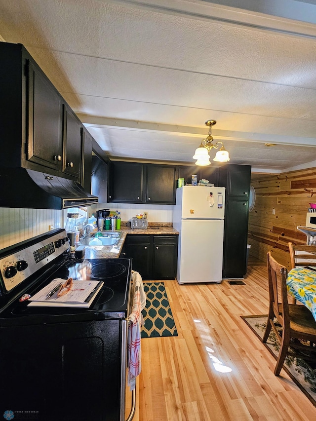 kitchen with dark cabinetry, freestanding refrigerator, stainless steel range with electric cooktop, light wood-style floors, and under cabinet range hood