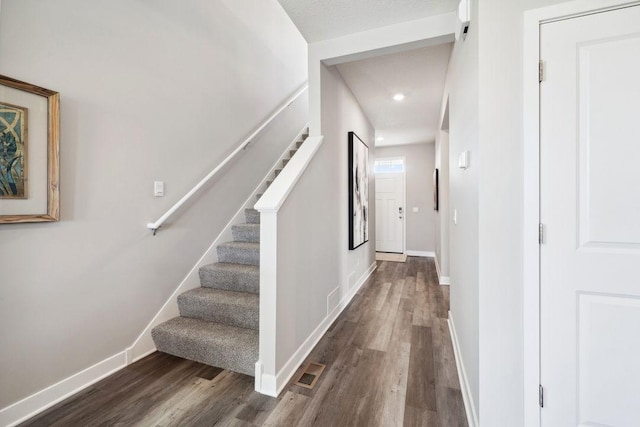 stairway featuring baseboards, visible vents, wood finished floors, and recessed lighting