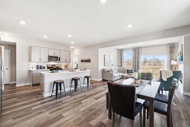 dining room featuring baseboards, wood finished floors, and recessed lighting