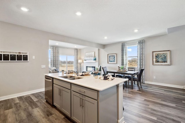 kitchen featuring dishwasher, dark wood-type flooring, a sink, and gray cabinetry