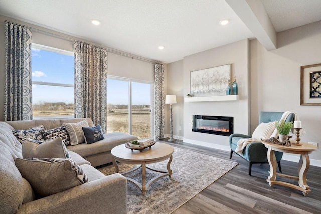 living area with wood finished floors, recessed lighting, a glass covered fireplace, and baseboards