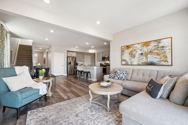 living area with dark wood-type flooring, recessed lighting, baseboards, and stairs