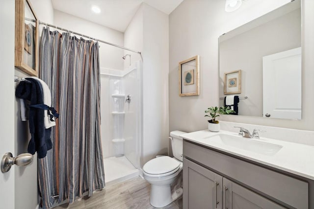 full bath with toilet, a stall shower, wood finished floors, and vanity