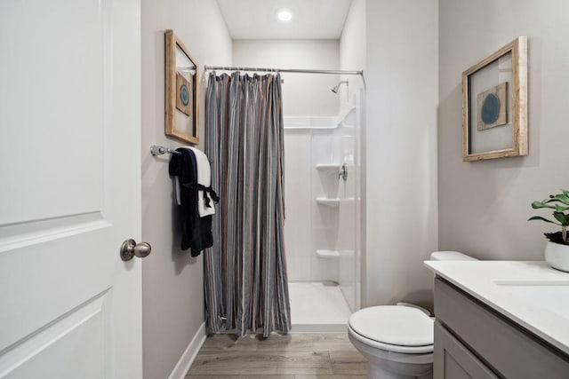 bathroom with vanity, a shower stall, toilet, and wood finished floors