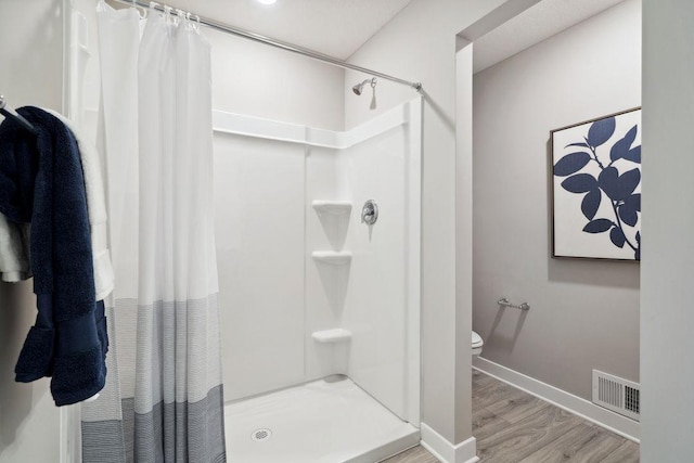 bathroom featuring a stall shower, baseboards, visible vents, toilet, and wood finished floors