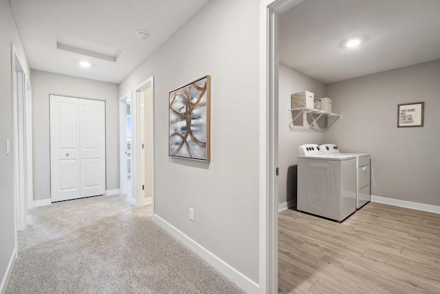 laundry area with laundry area, wood finished floors, washing machine and clothes dryer, and baseboards