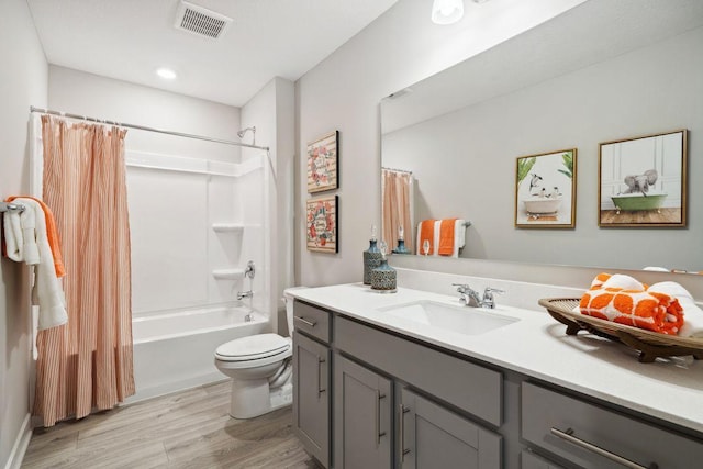 bathroom featuring toilet, wood finished floors, visible vents, vanity, and shower / bath combination with curtain