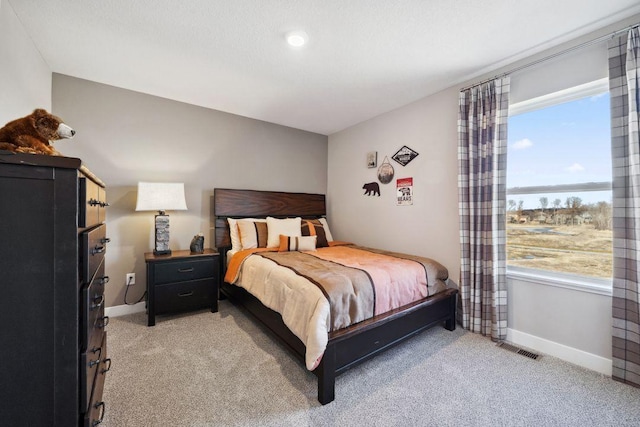 bedroom featuring light carpet, a water view, visible vents, and baseboards