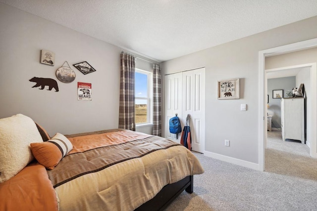 carpeted bedroom with a textured ceiling, baseboards, and a closet