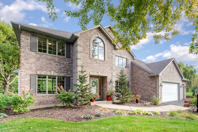 traditional home with aphalt driveway, brick siding, an attached garage, and roof with shingles