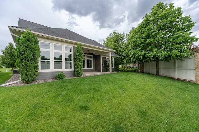 rear view of house featuring a patio area, roof with shingles, fence, and a yard