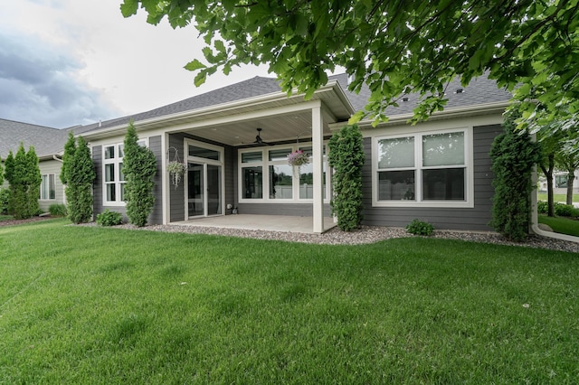 rear view of property with a yard, roof with shingles, a patio area, and a ceiling fan