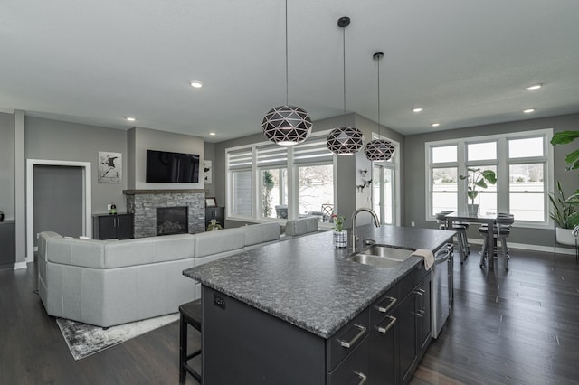 kitchen with plenty of natural light, a fireplace, dark wood finished floors, and a sink