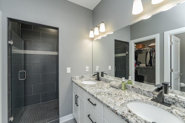 full bath with double vanity, a sink, a walk in closet, and a shower stall