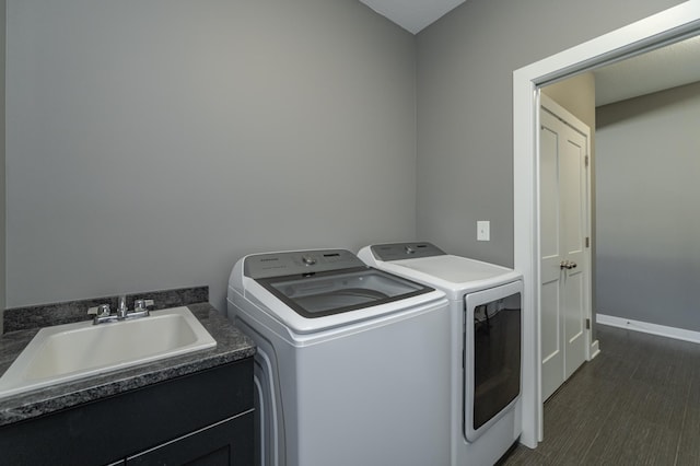 clothes washing area featuring laundry area, baseboards, dark wood-type flooring, separate washer and dryer, and a sink