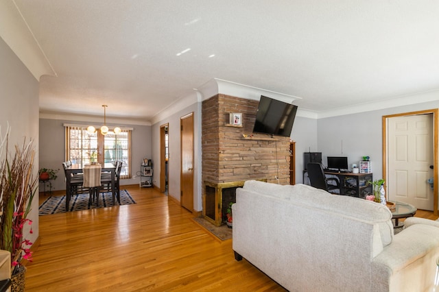 living room with light wood-type flooring, baseboards, ornamental molding, and a notable chandelier