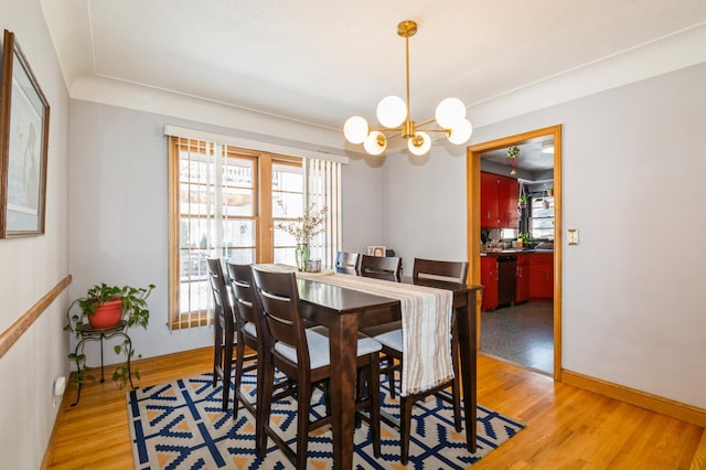 dining room with light wood-style flooring, a wealth of natural light, and a notable chandelier