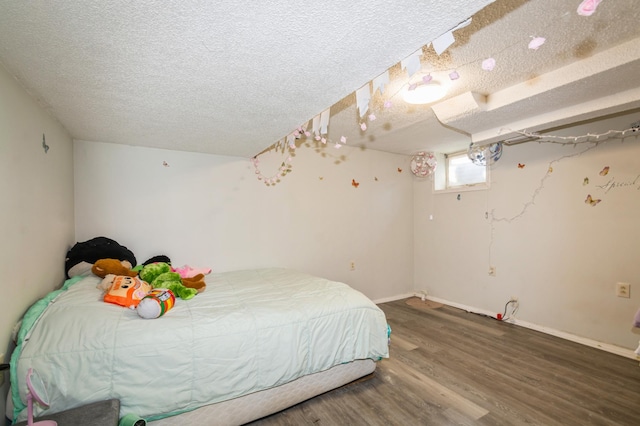 bedroom with a textured ceiling, baseboards, and wood finished floors