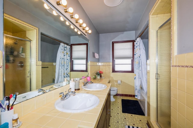 bathroom featuring toilet, a shower with shower curtain, a sink, and tile walls