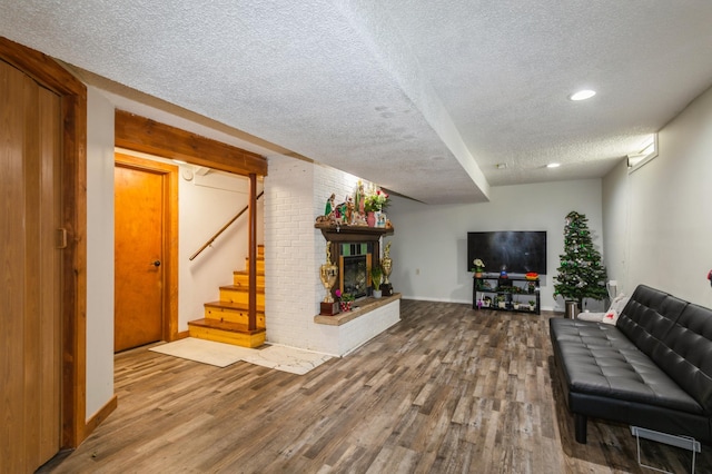 unfurnished living room featuring a textured ceiling, stairs, a fireplace, and wood finished floors