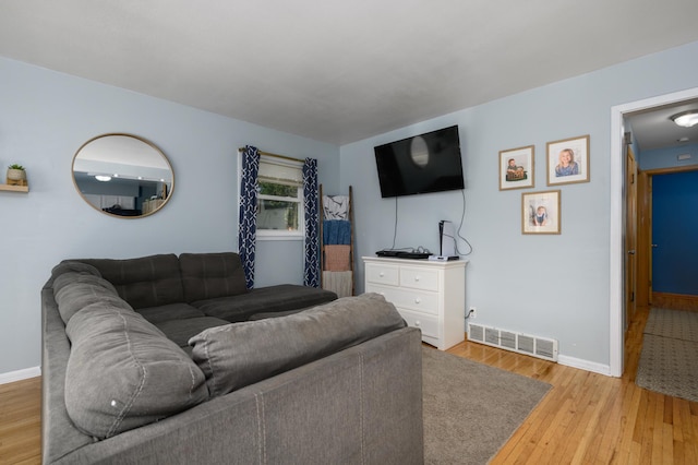 living room with visible vents, baseboards, and wood finished floors