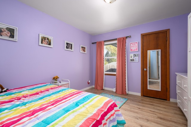 bedroom featuring light wood finished floors and baseboards