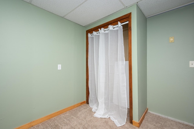 bathroom with a paneled ceiling and baseboards