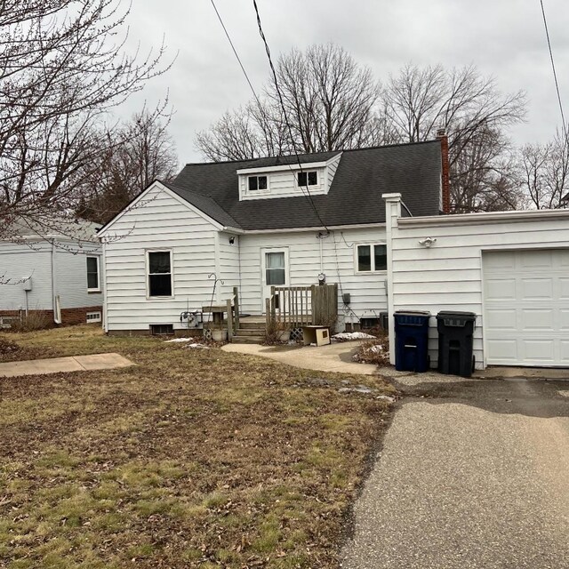 rear view of house with a garage, a shingled roof, a chimney, and aphalt driveway