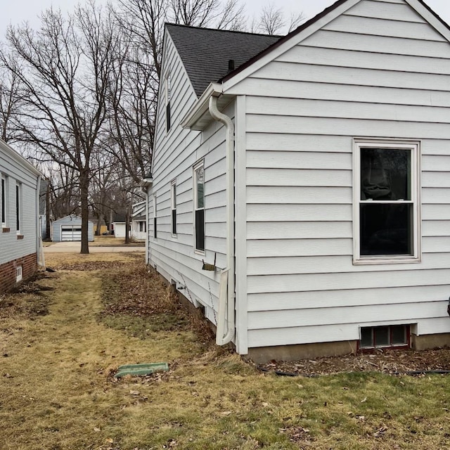 view of side of property with a lawn and roof with shingles