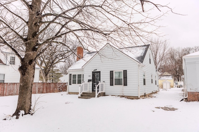 bungalow-style home with a chimney and fence