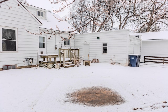 snow covered property with a garage and a wooden deck