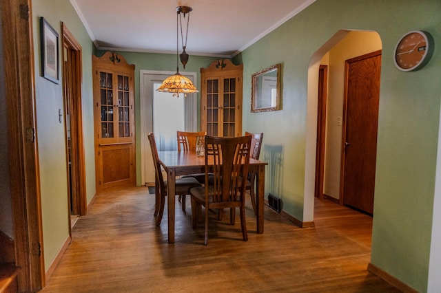 dining area with arched walkways, baseboards, and wood finished floors