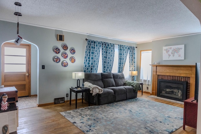 living area with crown molding, visible vents, arched walkways, and wood finished floors