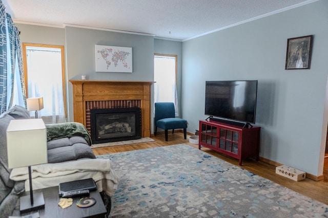 living area with baseboards, a fireplace with flush hearth, ornamental molding, and wood finished floors