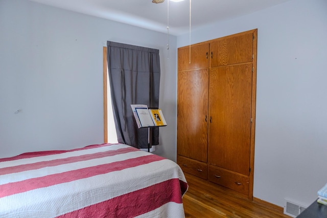 bedroom with a closet, wood finished floors, and visible vents