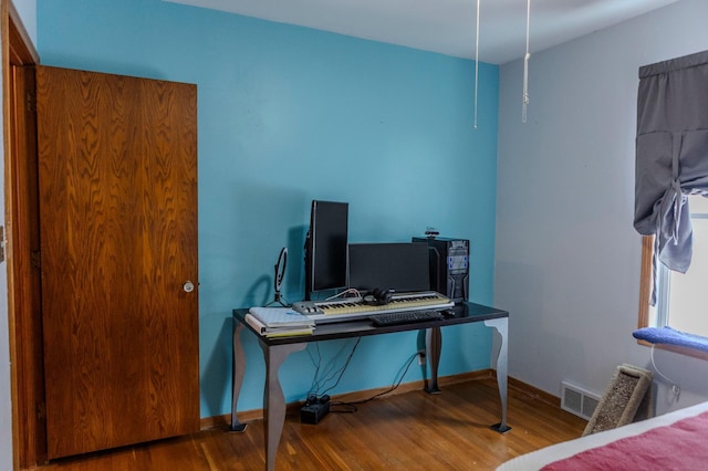 bedroom with visible vents, baseboards, and wood finished floors