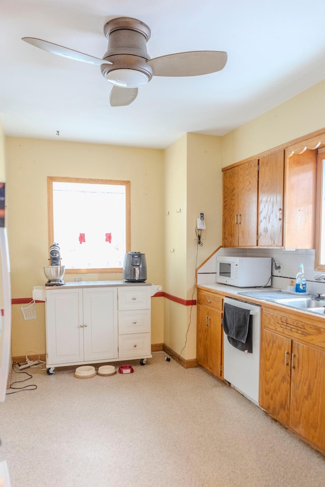 kitchen featuring light countertops, backsplash, a ceiling fan, a sink, and white appliances