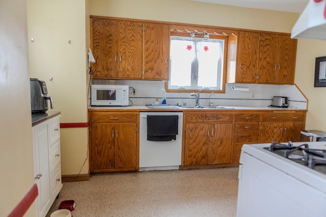 kitchen with white appliances, a sink, light countertops, backsplash, and brown cabinetry