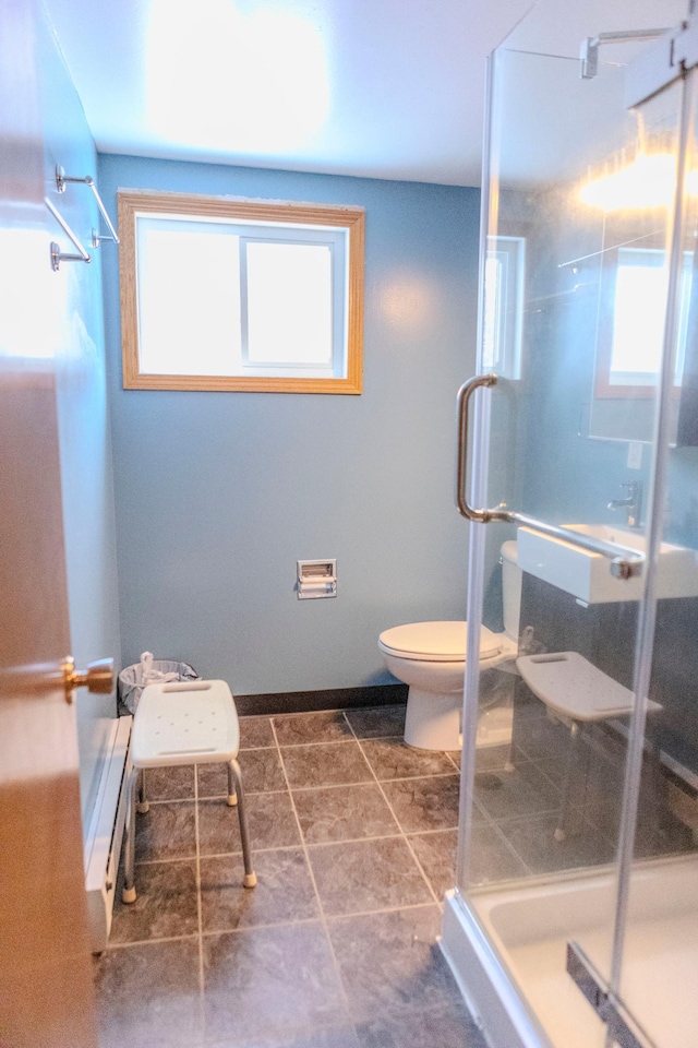 bathroom featuring toilet, a shower stall, and baseboards