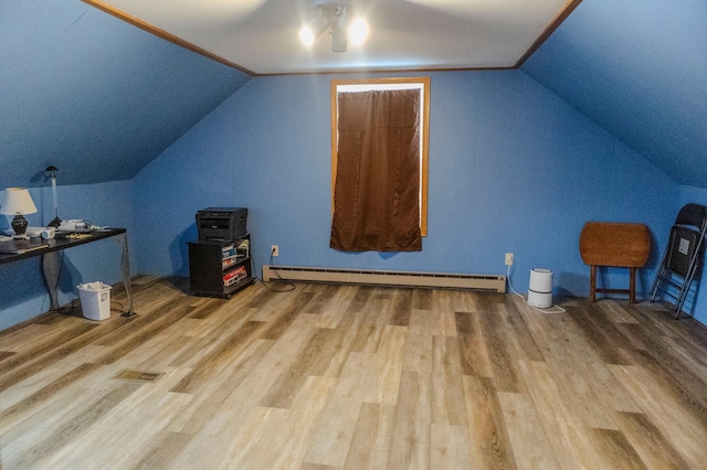 additional living space featuring lofted ceiling, visible vents, a baseboard heating unit, and wood finished floors