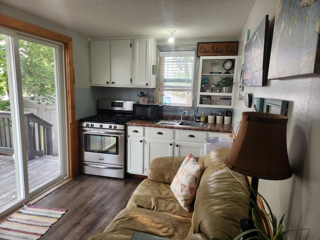 kitchen with dark countertops, white cabinetry, a sink, stainless steel gas range, and black microwave