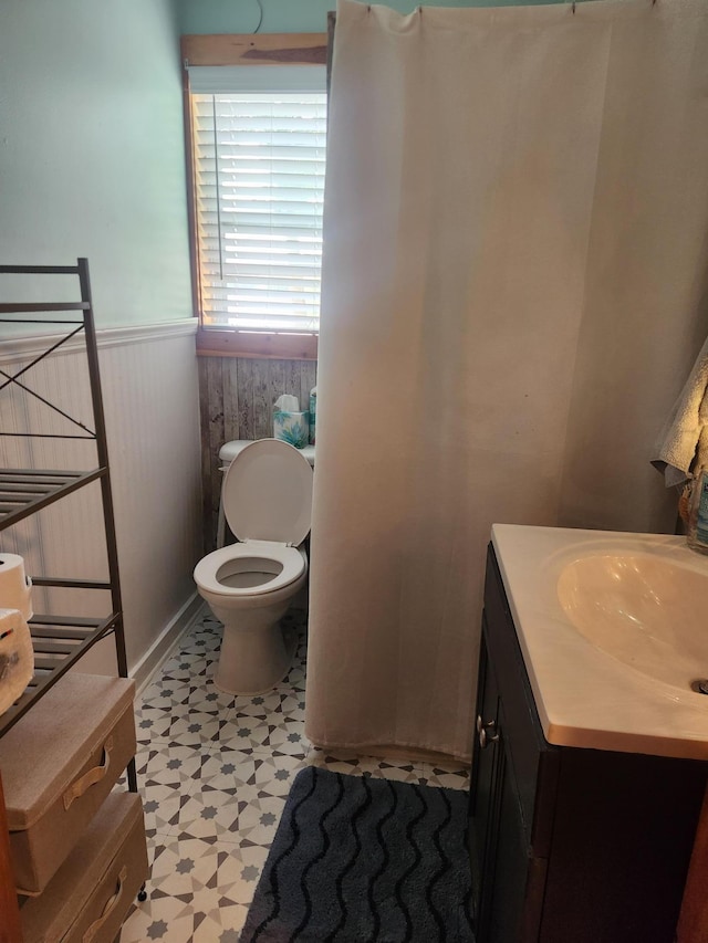 bathroom featuring toilet, a wainscoted wall, tile patterned floors, and vanity