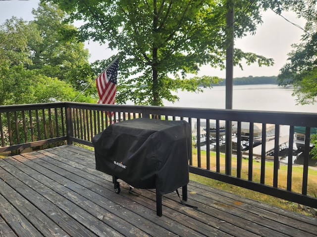 wooden terrace featuring a water view and a grill