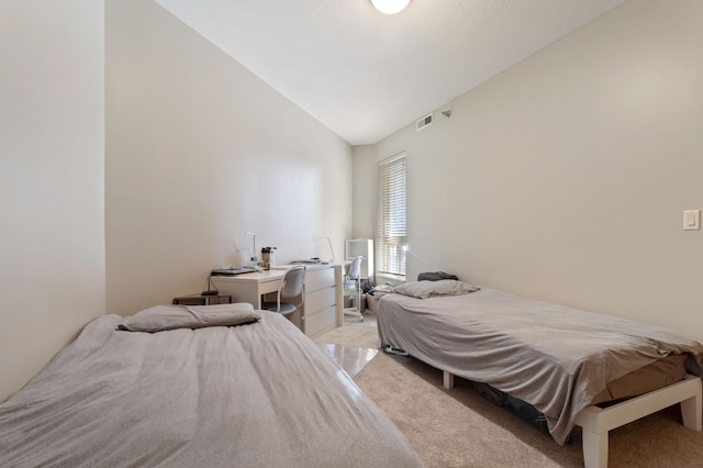 bedroom with lofted ceiling, light carpet, and visible vents