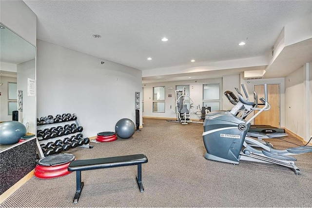 exercise room featuring a wall mounted AC, baseboards, a textured ceiling, and recessed lighting