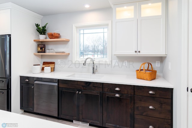 kitchen with a sink, dark brown cabinets, white cabinets, and freestanding refrigerator